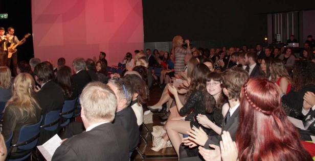 Ein Publikum applaudiert einer Band auf einer Bühne.