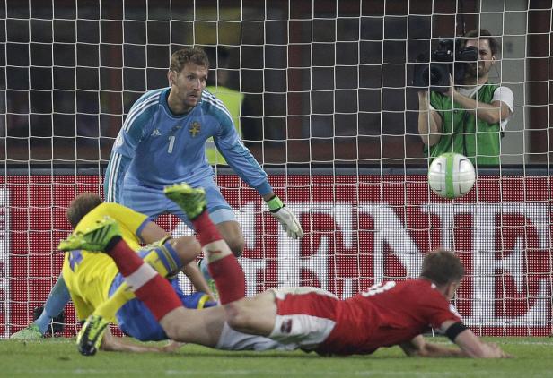 Ein schwedischer Torwart beobachtet, wie ein Ball auf das Tor zufliegt, während zwei Spieler zu Boden gehen.