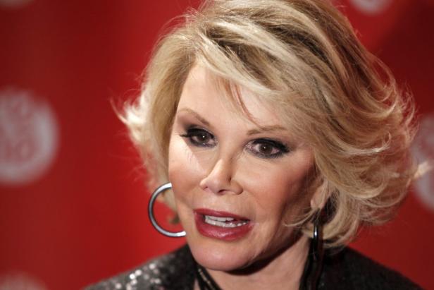 Joan Rivers posiert vor einem roten Hintergrund.