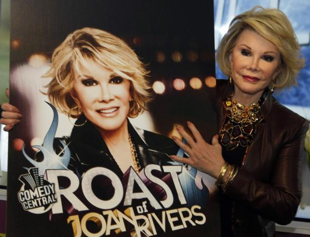 Joan Rivers posiert neben einem Plakat für „Comedy Central Roast of Joan Rivers“.