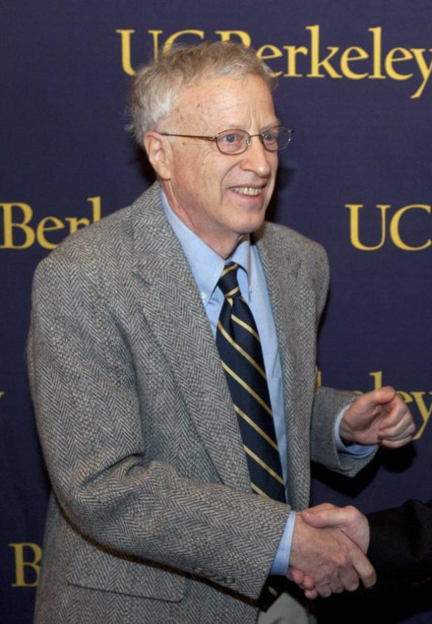 Ein Mann im Anzug schüttelt vor einem „UC Berkeley“-Hintergrund eine Hand.
