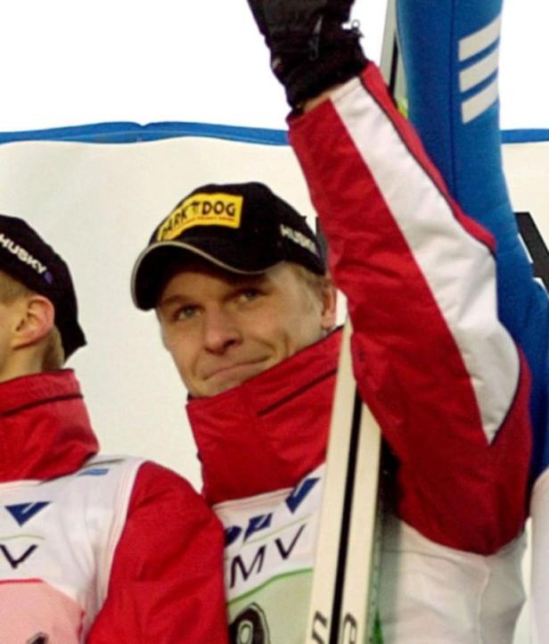 Ein Skispringer mit einer Kappe und einer rot-weißen Jacke jubelt.