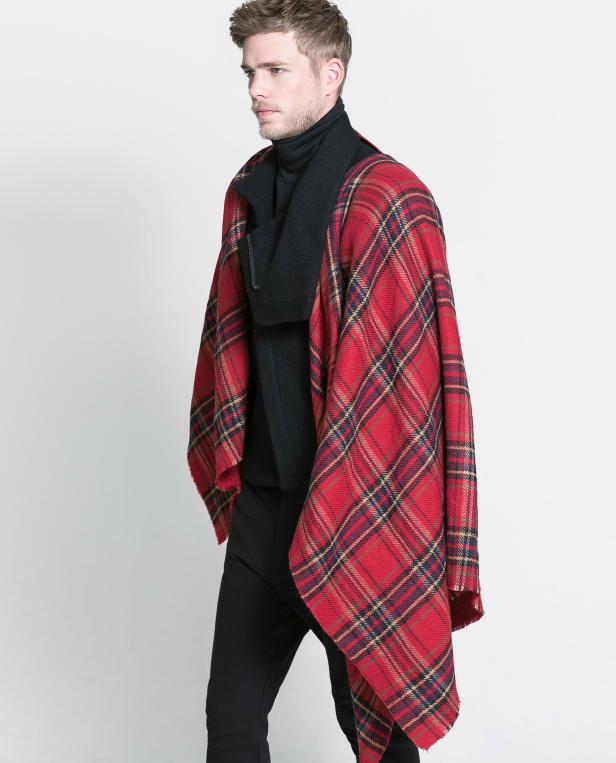 Ein Mann trägt einen schwarzen Rollkragenpullover und einen roten Überwurf mit Karomuster.