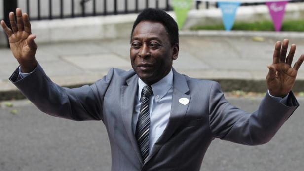Pelé in einem grauen Anzug winkt mit beiden Händen.
