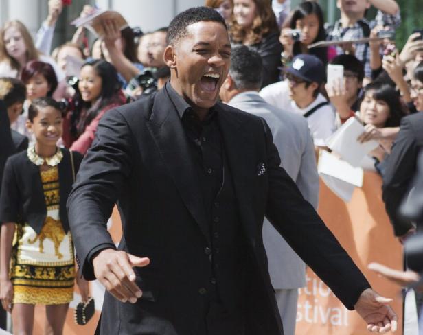 Will Smith lacht und gestikuliert vor einer Menschenmenge.