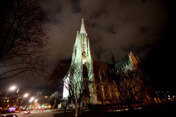 Die Votivkirche in Wien bei Nacht, beleuchtet von Scheinwerfern.