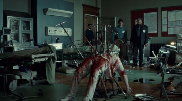 In einem chaotischen Krankenhauszimmer steht eine Leiche, die mit Metallstangen aufgespießt wurde.