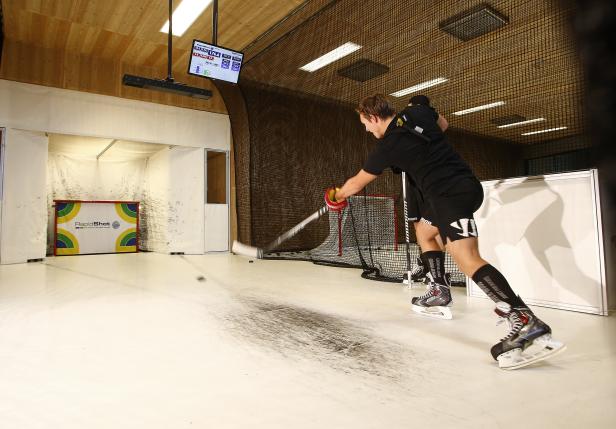 Ein Hockeyspieler schießt in einer Trainingshalle auf ein Tor.