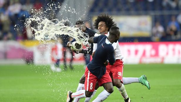 Fußballspieler feiern mit einer Champagnerdusche auf dem Rasen.