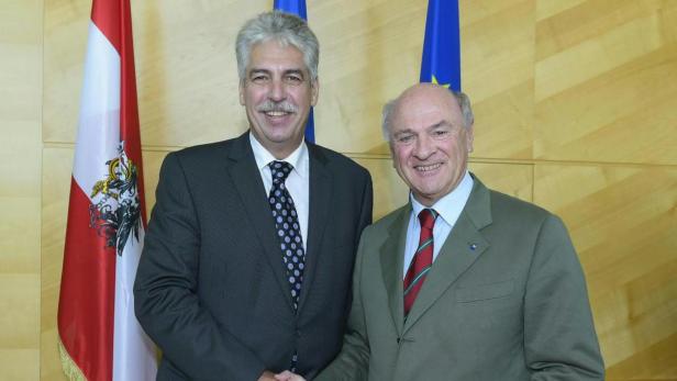 Zwei Männer posieren vor der österreichischen und der EU-Flagge.