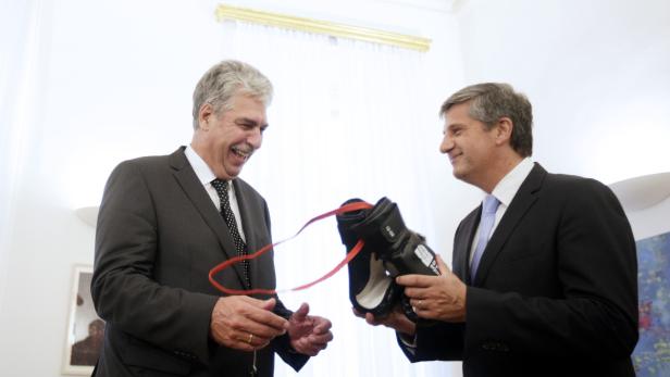 Zwei Männer in Anzügen tauschen Boxhandschuhe aus.