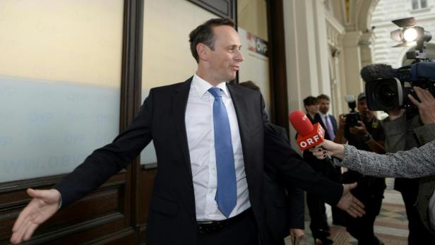 Ein Mann im Anzug wird von Reportern mit Mikrofonen interviewt.