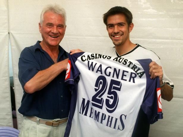 Zwei Männer halten ein Trikot von Casinos Austria mit der Nummer 25 und dem Namen Wagner.