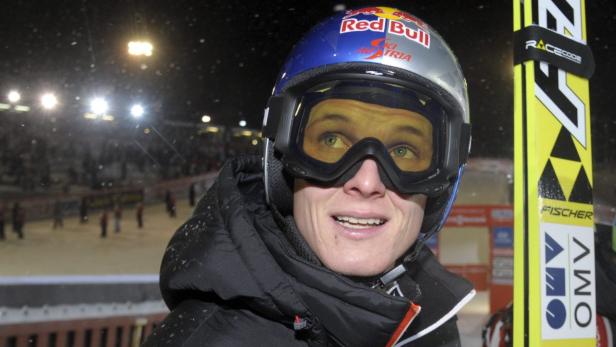 Ein Skispringer mit Helm und Skibrille blickt nach oben.