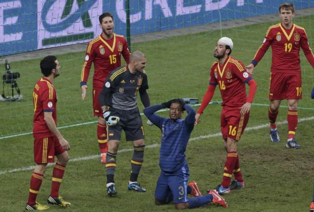 Ein frustrierter französischer Fußballspieler kniet vor spanischen Spielern.