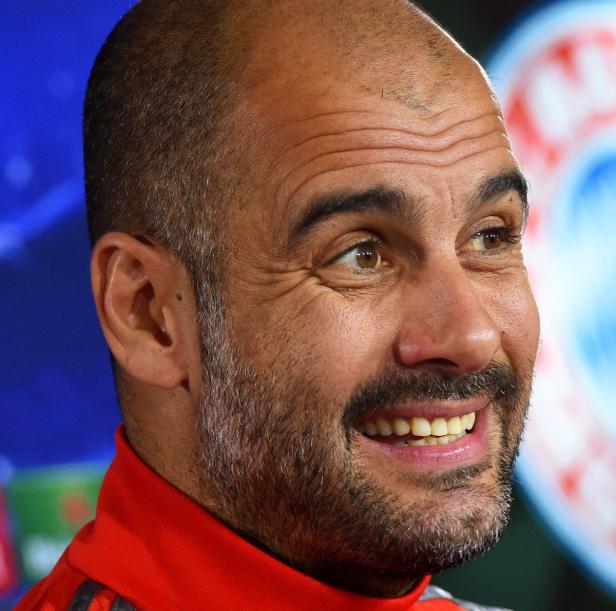 Ein lächelnder Pep Guardiola im roten Trainingsanzug.