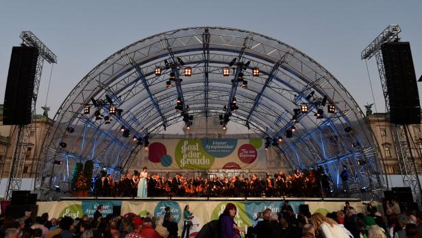 FEST DER FREUDE ZUM JAHRESTAG DER BEFREIUNG ÖSTERR Ein Orchester spielt unter einer großen Bühne mit dem Schriftzug „Fest der Freude“ vor Publikum.
