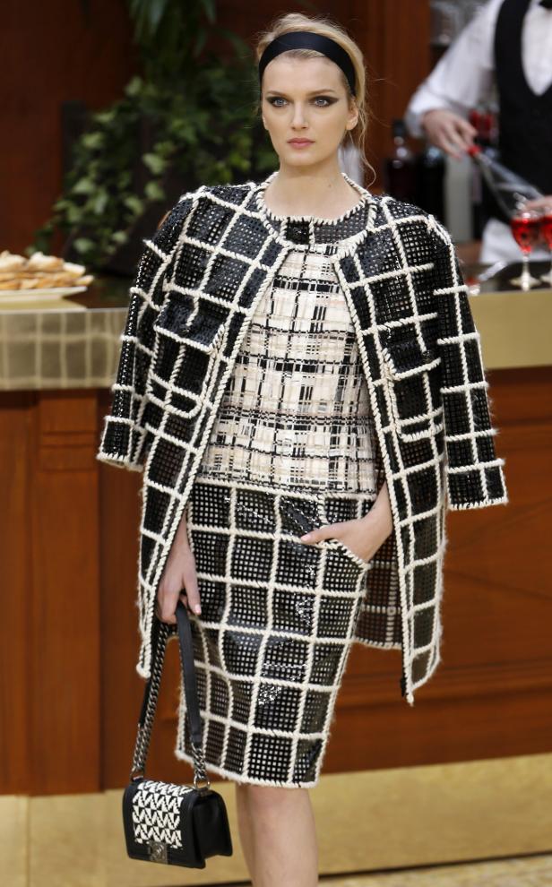 Eine Frau in einem schwarz-weiß karierten Chanel-Kostüm mit passender Handtasche.