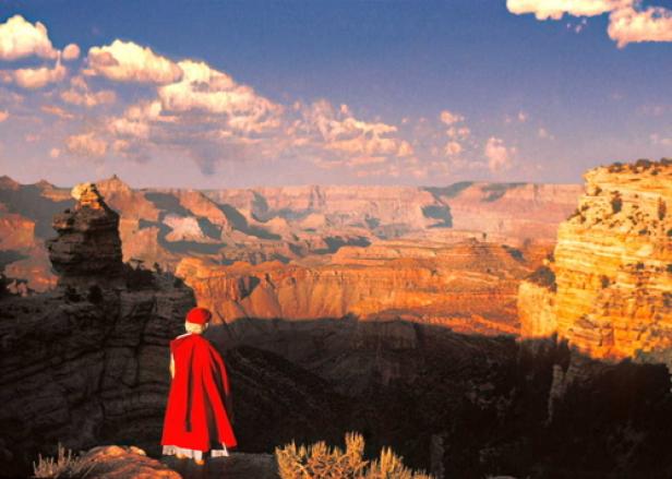 Eine Person in rotem Umhang blickt auf den Grand Canyon.