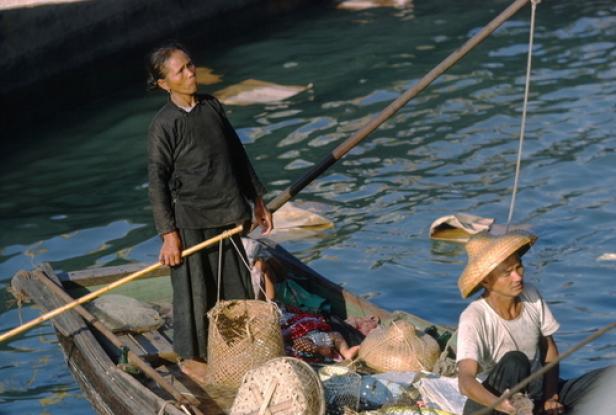 Zwei Personen fahren in einem kleinen Boot auf dem Wasser.