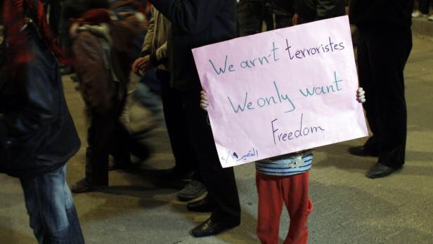 Ein Kind hält bei einer Demonstration ein Schild mit der Aufschrift „We arn't terroristes. We only want Freedom“.