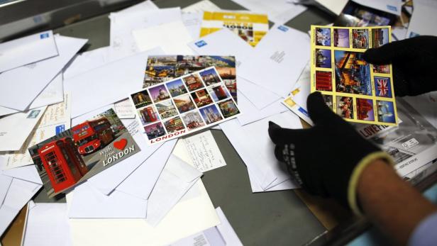 Postcards are sorted at Mount Pleasant sorting off Eine Person sortiert Postkarten und Briefe mit London-Motiven.