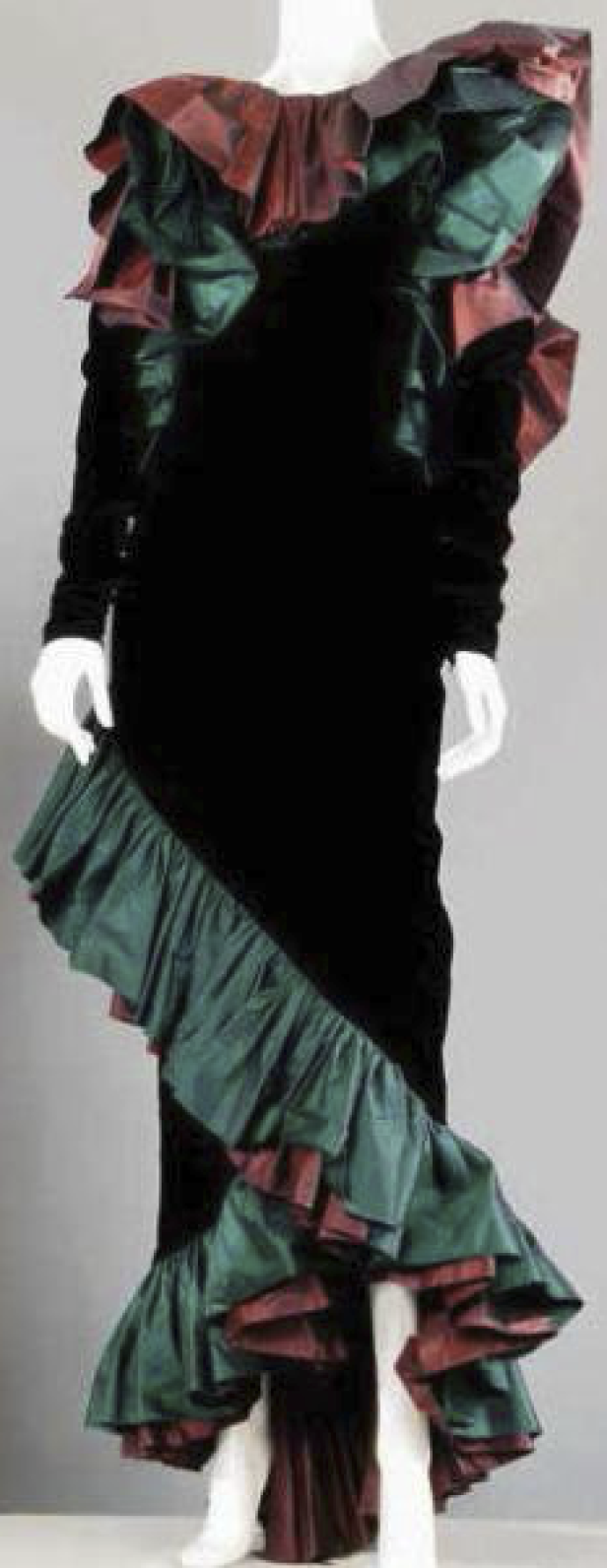 Ein langes, schwarzes Samtkleid mit grünen und roten Rüschen an Schultern und Saum.