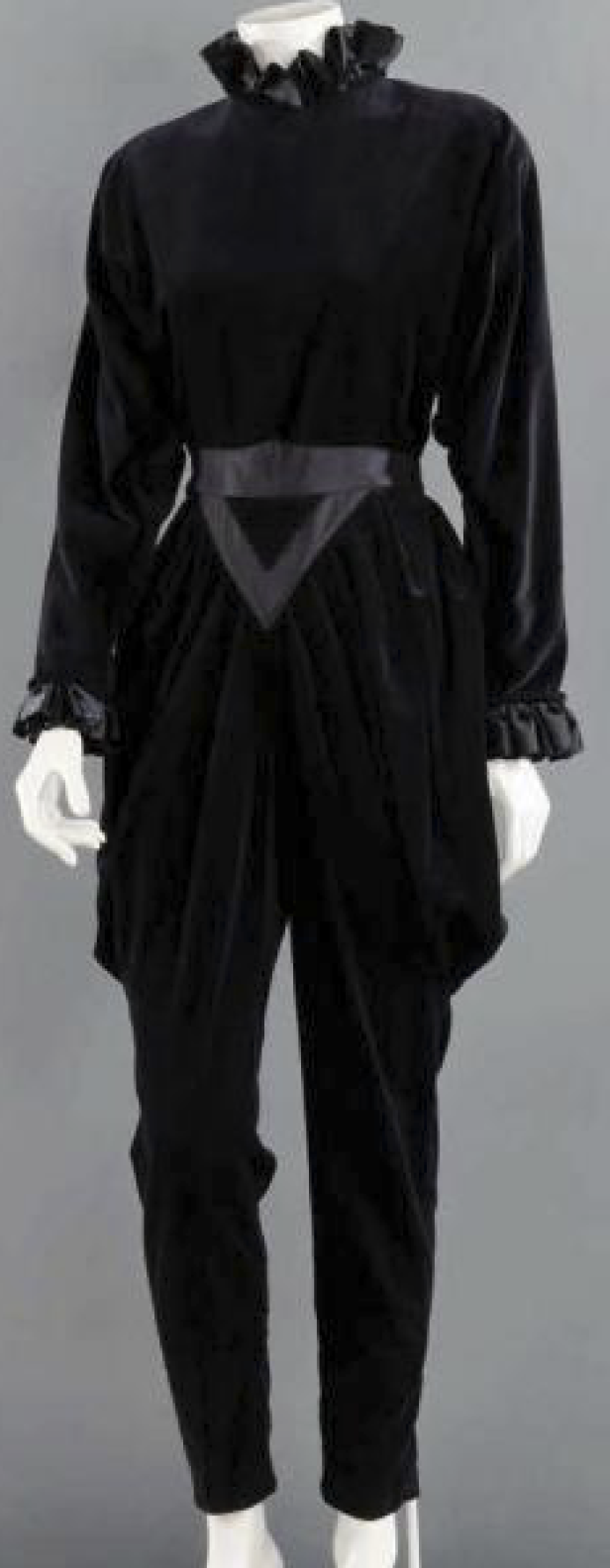 Ein schwarzer Samtanzug mit Rüschenkragen und Zierschärpe auf einer Schaufensterpuppe.