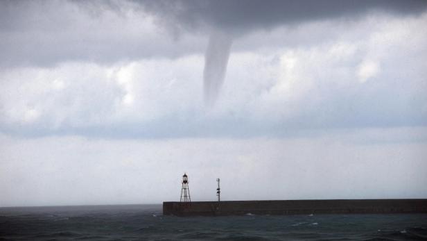 Ein Wasserhose erstreckt sich vom Himmel über das Meer.