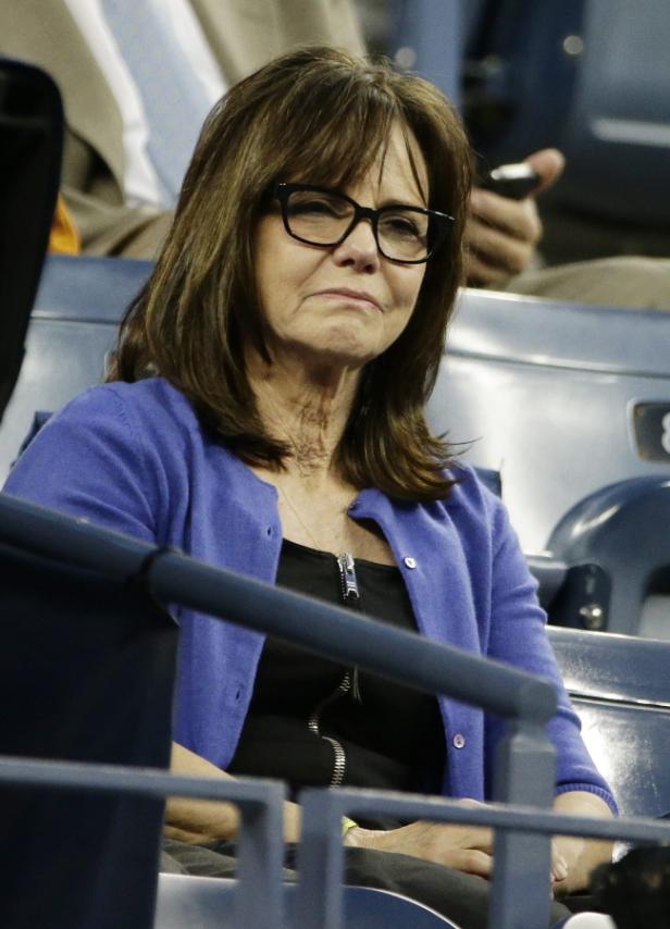 Sally Field sitzt auf einem blauen Sitzplatz und schaut mit traurigem Gesichtsausdruck zu.