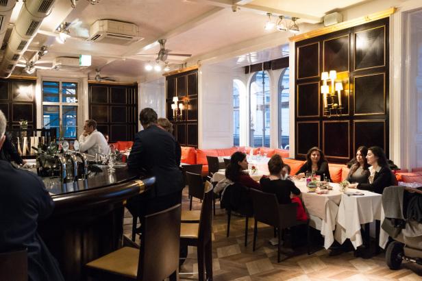 Gäste sitzen an Tischen in einem eleganten Restaurant.