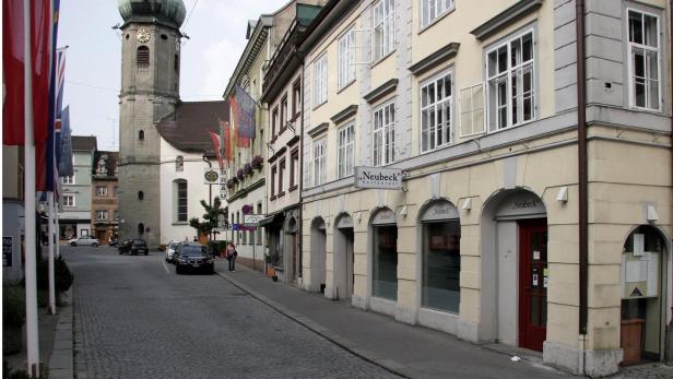 Blick auf eine Straße in einer Stadt mit dem Restaurant „Neubeck“ und einem Kirchturm.
