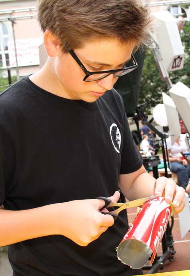 Ein Jugendlicher schneidet eine Coca-Cola-Dose mit einer Schere.
