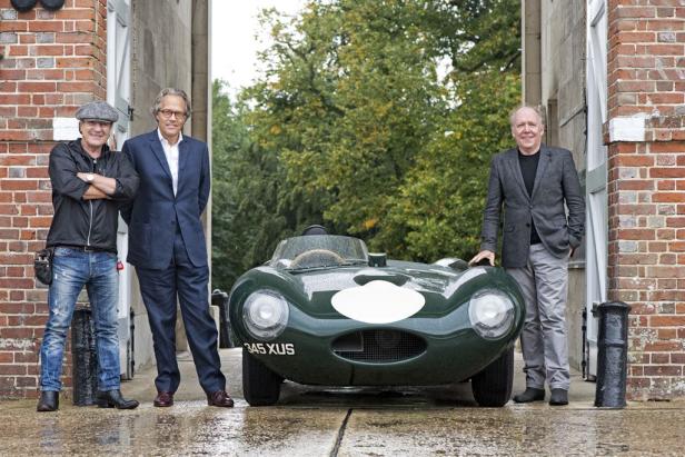 Drei Männer posieren vor einem grünen Jaguar D-Type Oldtimer.
