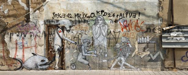 Eine Wand mit Graffiti-Kunst, die verschiedene Figuren und Symbole darstellt.