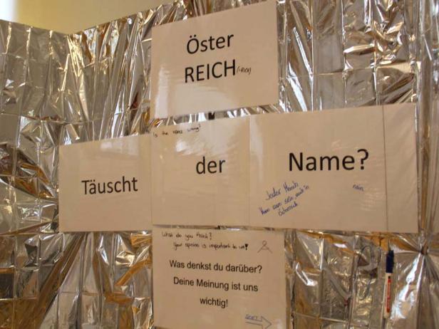 Eine Wand mit Zetteln, auf denen Wörter wie „Österreich“, „Täuscht“ und „Name?“ stehen.