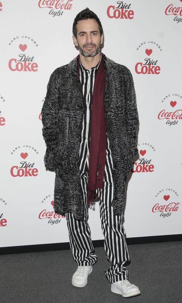 Marc Jacobs posiert vor einer Wand mit Diet Coke-Logos.