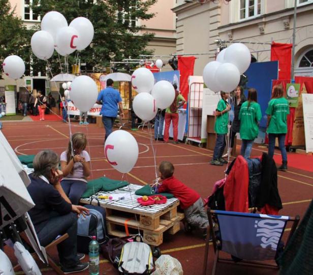 Kinder spielen auf einer Veranstaltung mit weißen Luftballons mit roten Buchstaben.
