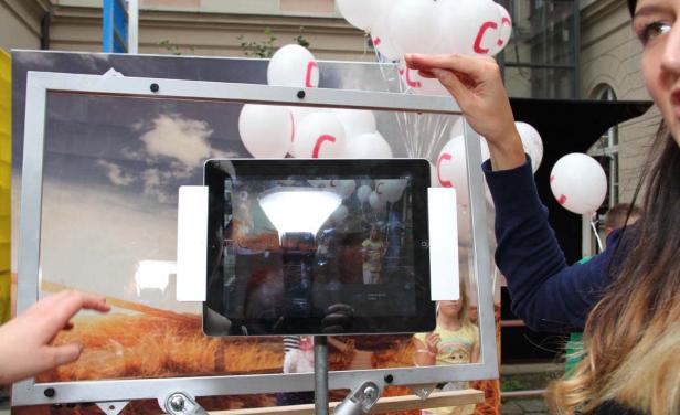 Eine Frau interagiert mit einer Installation, die einen Bildschirm und Ballons kombiniert.