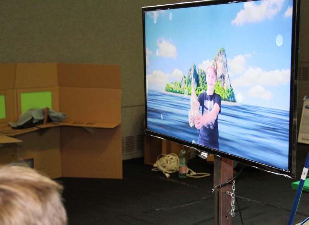 Ein Junge hält einen Fisch vor einem animierten Hintergrund mit Meer und Inseln.