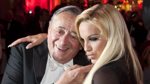 Archaisches Beuteschema hüben wie drüben: Lugner und Lohfink beherrschen das Spiel. Ein älterer Mann im Smoking posiert mit einer blonden Frau.