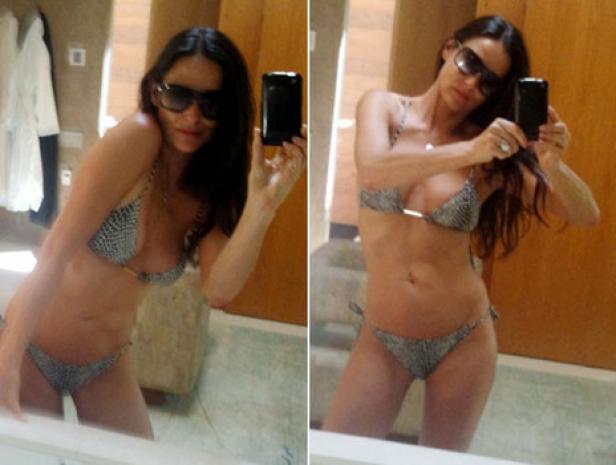Eine Frau mit Sonnenbrille macht ein Selfie im Badezimmer, bekleidet mit einem Bikini mit Schlangenmuster.
