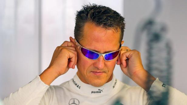 Michael Schumacher setzt eine verspiegelte Sonnenbrille auf.