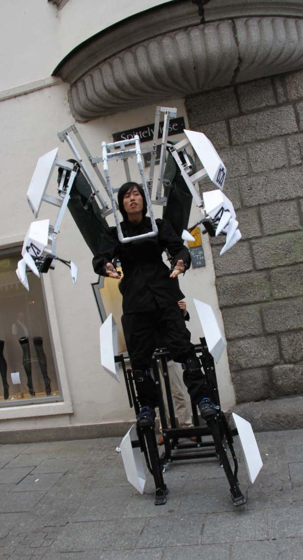 Eine Frau in einem Roboter-Kostüm steht auf einer Straße.