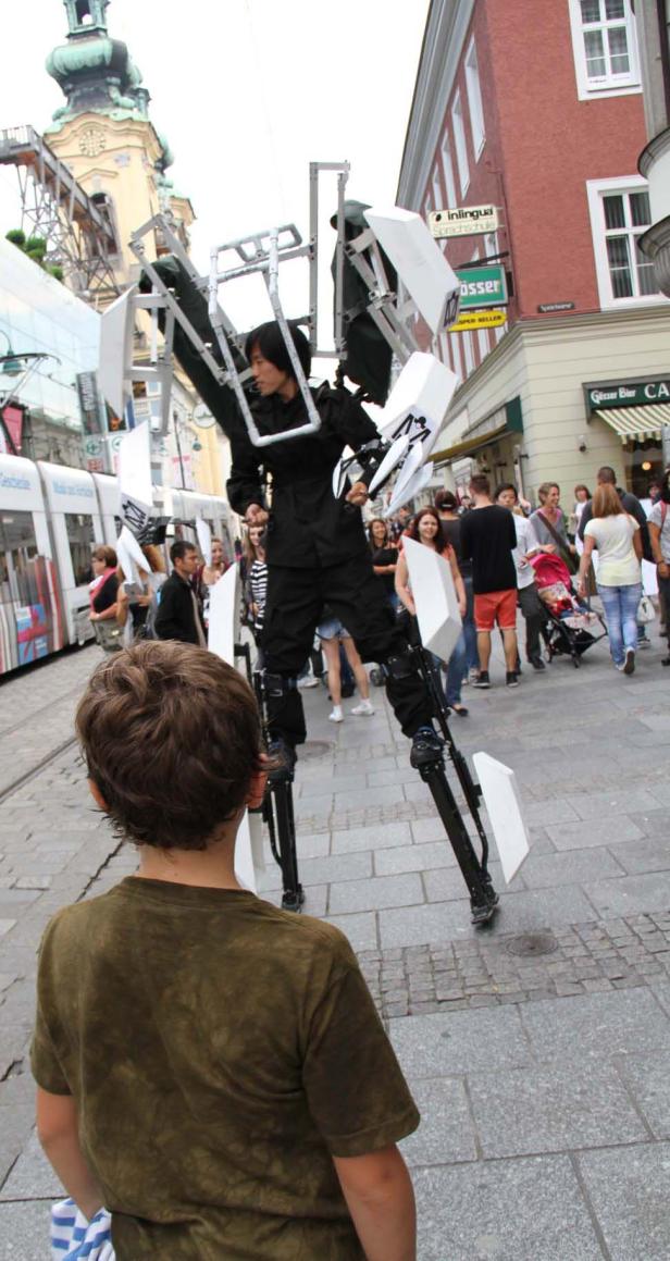 Ein Mann in einer Roboter-ähnlichen Kostümperformance auf einer belebten Straße.