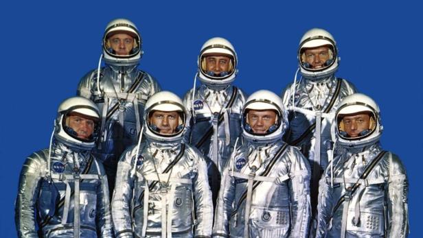 Carpenter (vorne recht) im NASA-Einsatz Die „Mercury Seven“-Astronauten der NASA in ihren Raumanzügen vor blauem Hintergrund.