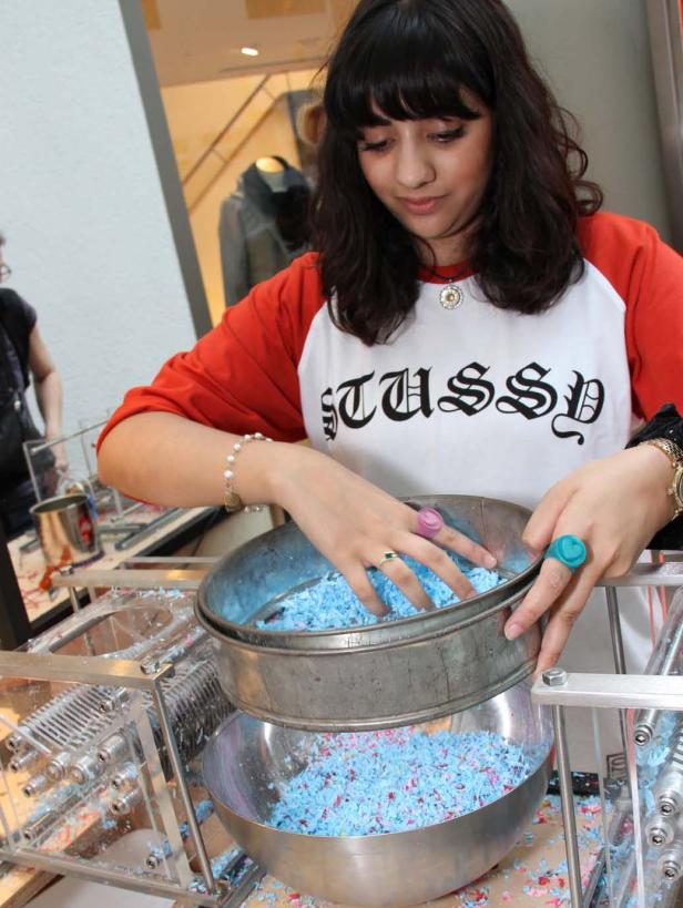 Eine Frau siebt blaue Papierstücke mit einer Maschine.