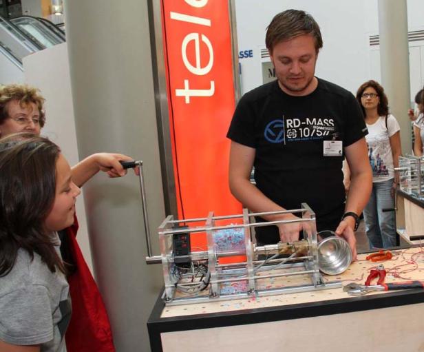 Ein Mädchen bedient eine Maschine, während ein Mann ihr dabei hilft.