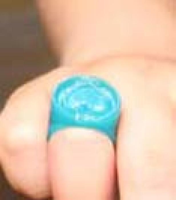 Ein türkisfarbener Ring aus Plastik auf einem Finger.