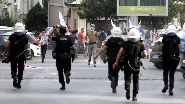 Polizisten verfolgen Demonstranten in einer städtischen Umgebung.